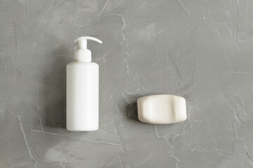White soap bar and liquid soap in white bottle Top view with copy space on gray background