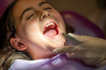 Cute little girl in dentist studio undergoing dental cleaning