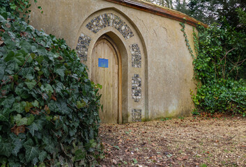 wooden cathedral arch door in a rendered stone wall leading to the vicarage garden