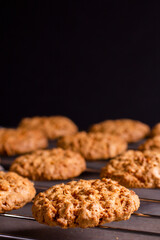 Freshly baked warm oatmeal cookies on a cooling rack on a dark background