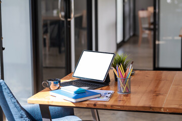 Mock up of a white screen tablet, coffee mug with documents placed on a wooden table in the office.