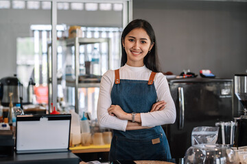Fototapeta na wymiar Image of an Asian woman barista wearing an apron at the café owner. Looking at camera.