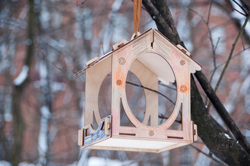 Bird feeder made of wood on a tree branch. Background. Winter painting.