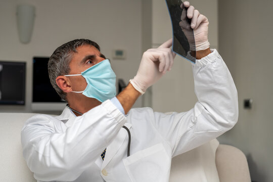 Doctor Wearing Face Mask Looking At X-ray Backlit