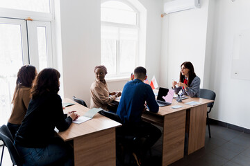 Multiethnic students and teacher study foreign languages together in class. Studing with laptop....