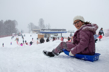 Happy girl enjoying a sleigh ride. Child sledding. Happy child enjoying winter holidays in Tufandag...