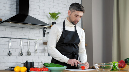 Man chef in black apron at home kitchen sliced fresh cherry tomato teaches student housewife online...