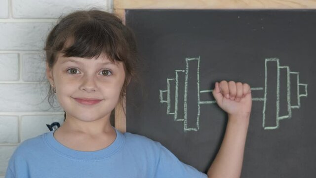 The concept of a strong child in learning. Cute little girl with a drawn dumbbell.