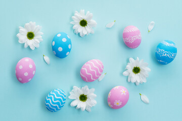 Obraz na płótnie Canvas Easter decoration. Festive composition. Spring ornament. Creative arrangement of painted pink blue eggs white daisy flowers petals isolated on light pastel background.