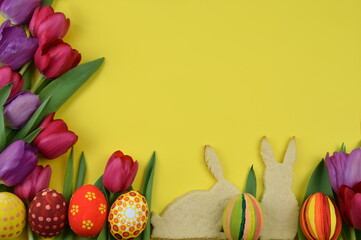 tulips, painted eggs, bunnyshaped cookies on yellow background