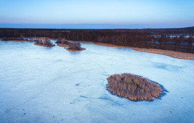 Aerial drone fly air shot, view on ice lake frozen winter top down road moody mood grey blue Saxony germany Guttau