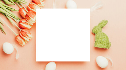 Easter card. Golden, white colour egg in basket with spring tulips, feathers on pastel pink background in Happy Easter decoration. Flat lay, top view with copy space.