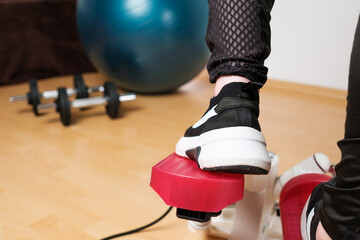Back view on the woman feet in sneakers doing exercising on the twist stepper or stair stepper...
