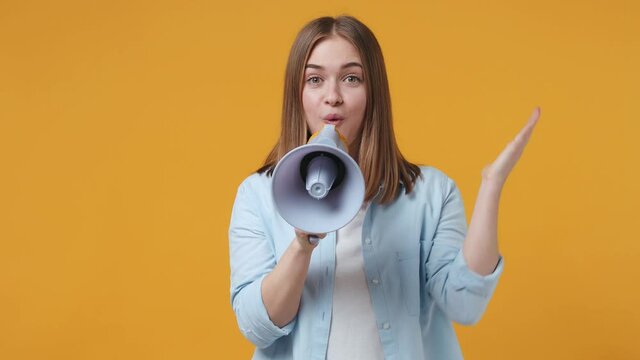 Shocked crazy blonde young woman 20s years old in casual blue shirt posing isolated on yellow color background studio. People sincere emotions lifestyle concept. Screaming in megaphone spreading hands