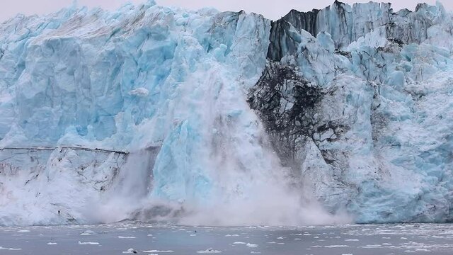 Ice melts and falls high from the glacier in Alaska 