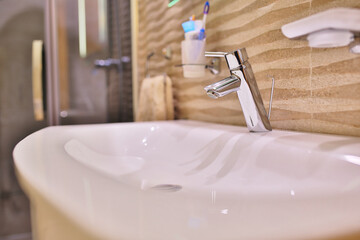 Luxury faucet mixer on a white sink in a beautiful gray interior bathroom. close up view of nice...