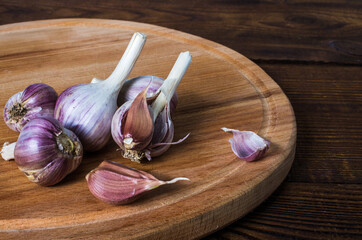 heads of garlic on a cutting board made of wood, round shape. Rustic style