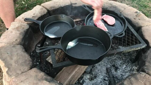 Cooking pork chops in Dutch oven cast iron skillets over an open campfire