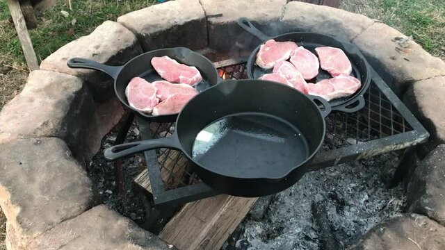 Cooking pork chops in Dutch oven cast iron skillets over an open campfire