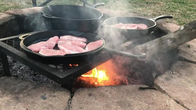 Cooking pork chops in Dutch oven cast iron skillets over an open campfire
