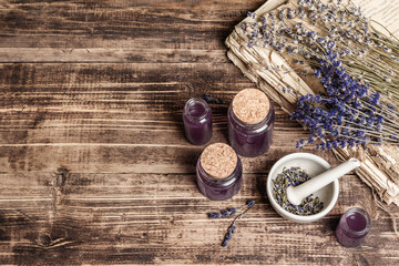 Dried lavender flowers in a in a mortar and pestle with bottle of essential lavender oil or infused water