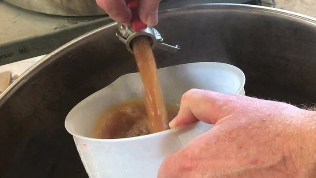 pouring hot steaming wort from mash tun into beer brew kettle