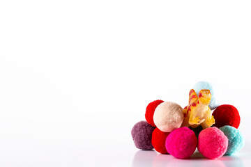 Toy dinosaur emerging from colored sponge balls.The photo is a horizontal shot taken on a white background in a studio.
