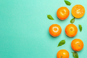 Ripe juicy tangerines and fresh leaves on turquoise summer background