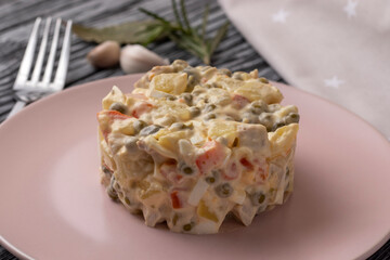 Olivier salad with meat and vegetables. Close-up. On a black wooden table.
