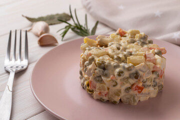 Olivier salad with meat and vegetables. On a white wooden table. Close-up.