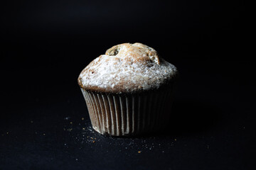 Cupcake with  raisins on a black background close-up.