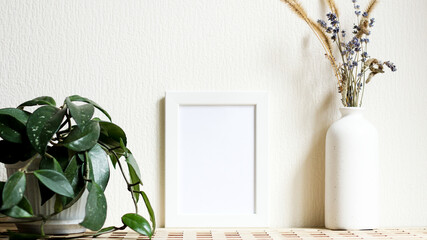 Poster with copy space. Mockup of a wooden frame with home plant liana with vase with dried flowers. White, minimalism. copy space. Mock up design.