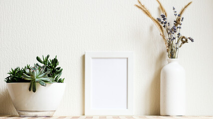 Poster with copy space. Mockup of a wooden frame with home plant succulents, with vase with dried flowers. White, minimalism. Mock up design.