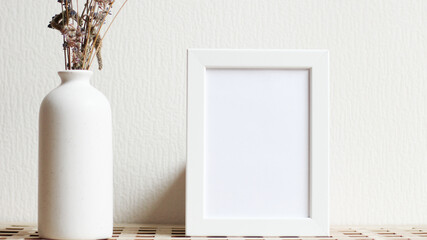 Poster with copy space. Mockup of a wooden frame with with vase with dried flowers. White, minimalism. Mock up design.