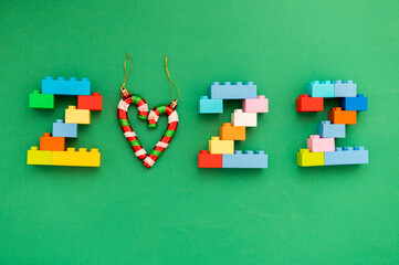 multicolored numbers 2022 from kids constructor set on isolated green background with place for text