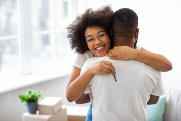 Excited African Spouses Hugging Holding New House Key Indoor