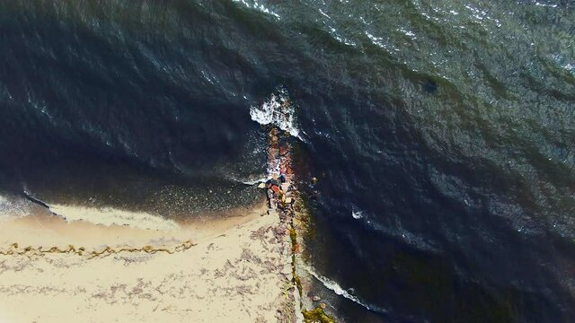 Steady drone shot of small waves hitting the beach at the baltic coast in Denmark. 