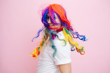Young man with dyed in different colors hair, on a pink background.
