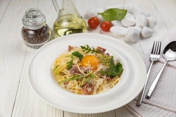 Pasta with egg and parmesan on a white wooden table

