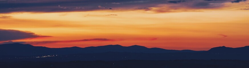 Atardecer en la Sierra de Guadarrama en Madrid, España. Cielo anaranjado con los últimos rayos del sol resaltando la silueta de las montañas ubicadas al norte de Madrid.