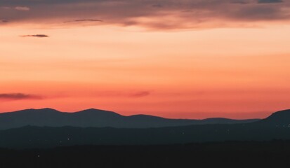 Atardecer en la Sierra de Guadarrama en Madrid, España. Cielo anaranjado con los últimos rayos del sol resaltando la silueta de las montañas ubicadas al norte de Madrid.