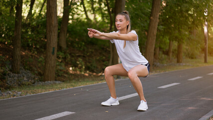 Woman runner stretching legs before exercising summer park  morning