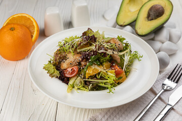 Salad with herbs and meat on a white wooden table
