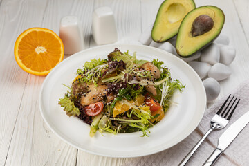 Salad with herbs and meat on a white wooden table
