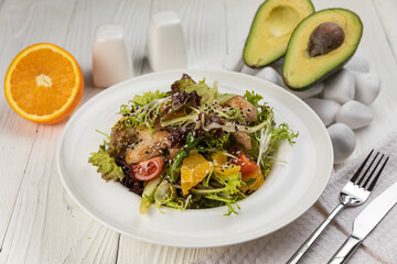 Salad with herbs and meat on a white wooden table
