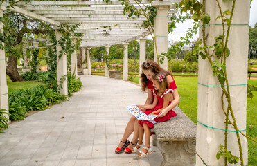 mother with daughter reading children's book in the park