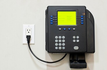 Electronic digital time clock display company business attached to wall plugged in outlet.