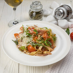 Pasta with herbs and tomatoes on a white wooden table
