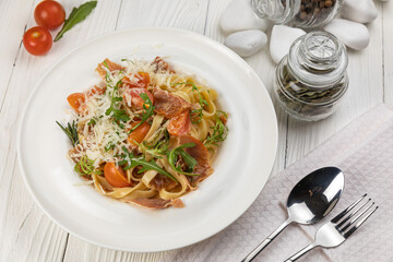 Pasta with herbs and tomatoes on a white wooden table
