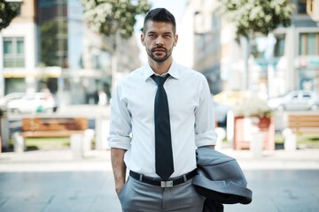 Portrait of good-looking young adult businessman outdoors on street wearing suit and tie.